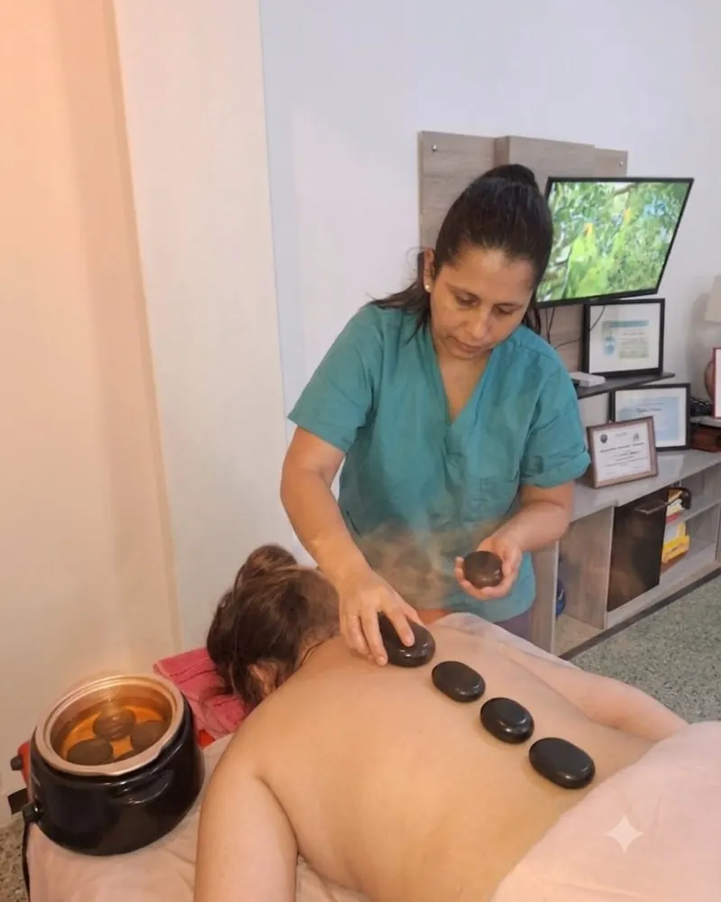 Piedras calientes alineadas sobre la espalda junto a flores de orquídea